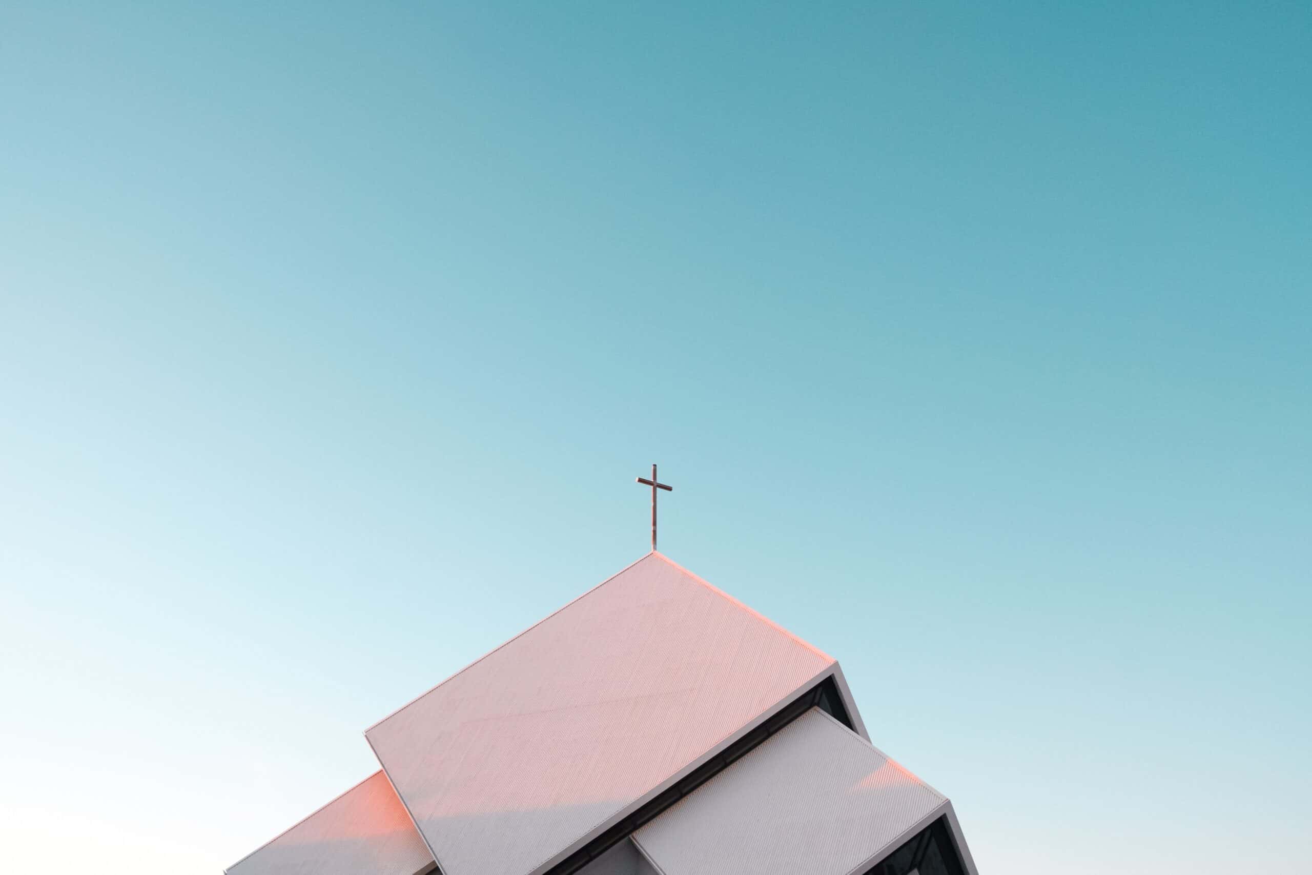 A crucifix on a religious building, with blue skies behind